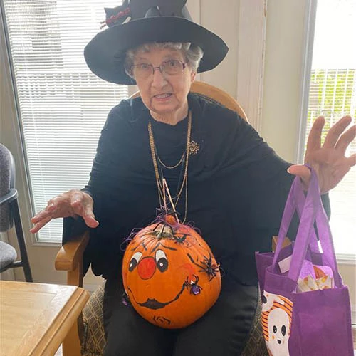 Woman dressed as a witch holding a pumpkin