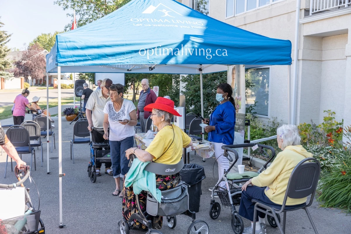 Residents outdoors enjoying some nice weather together. An Optima Living tent is providing them with some shade as well.