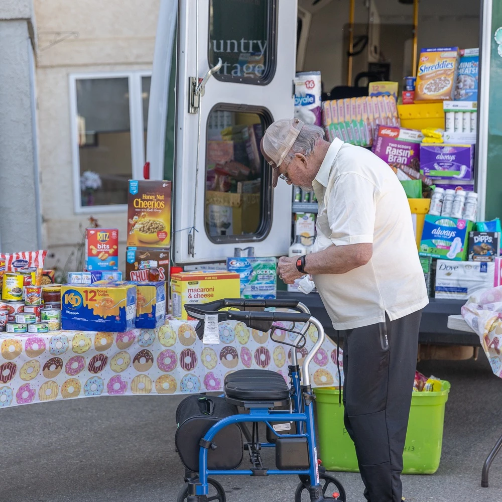 Resident standing in front of the bus full of food for the food bank.