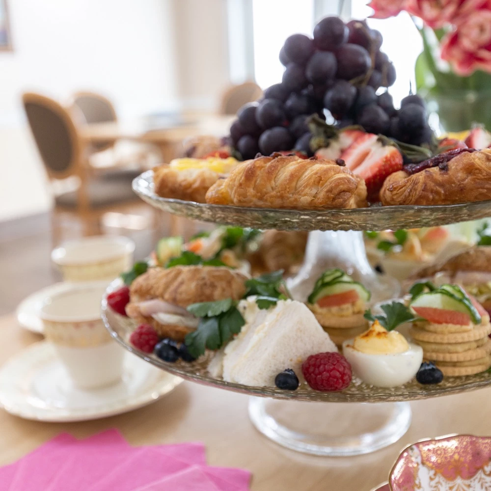 Tray full of food for residents to enjoy with croissants, grapes, eggs, and crackers most prominent.