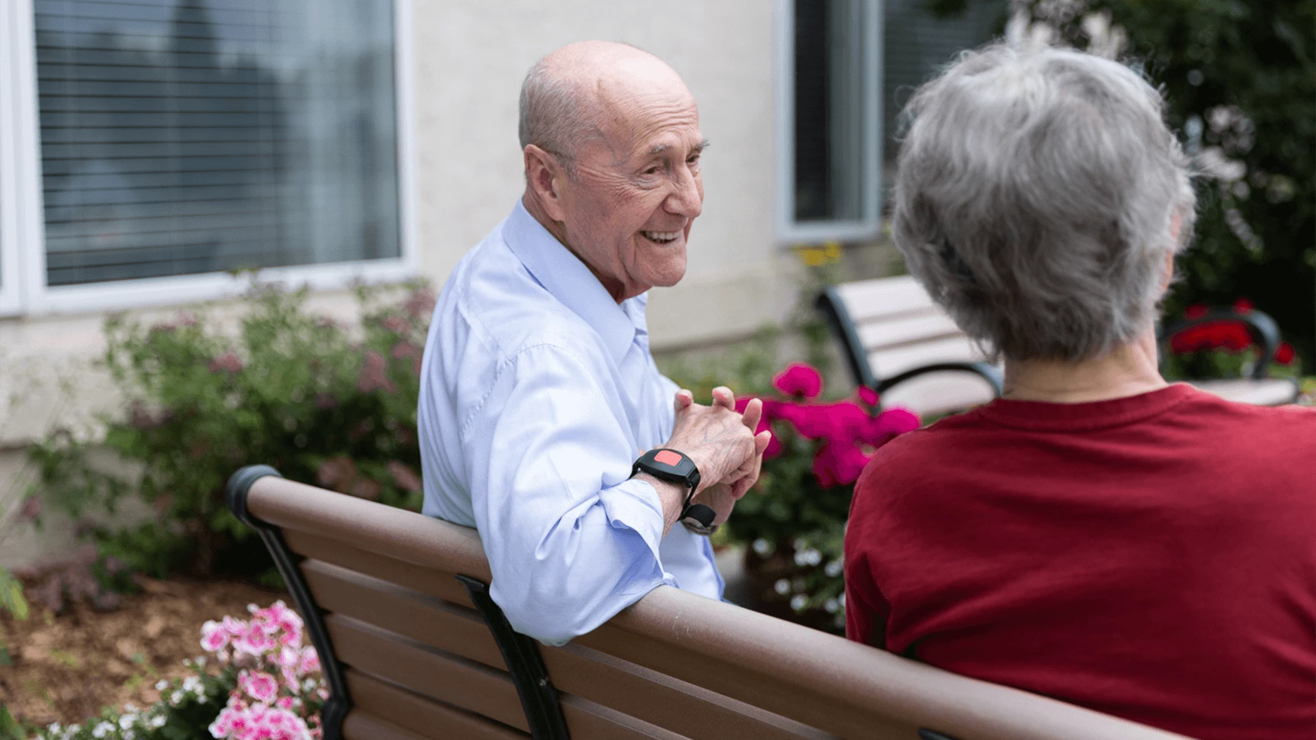 An elderly couple talking and smiling while sitting outside