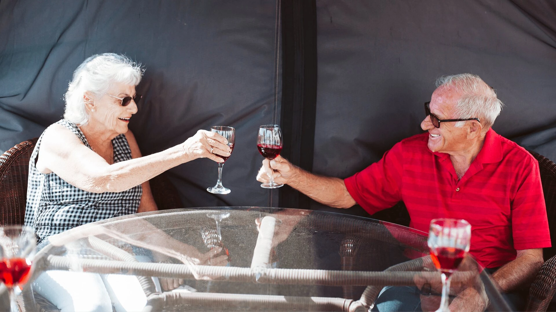 An elderly couple laughing and drinking wine