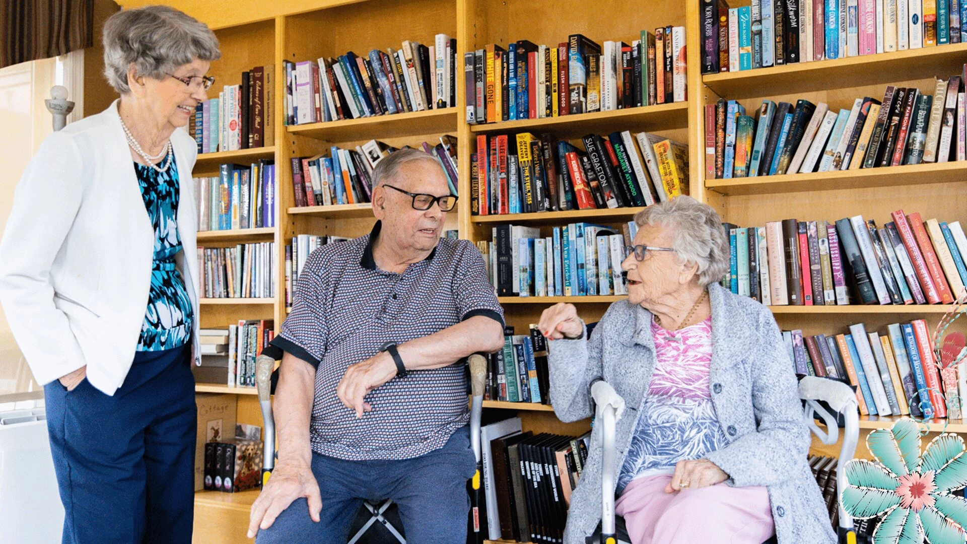 Two elderly women and a man talking in library at CC