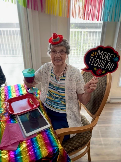 Senior enjoying Cinco de Mayo with decorations! She is holding a sign that says, 